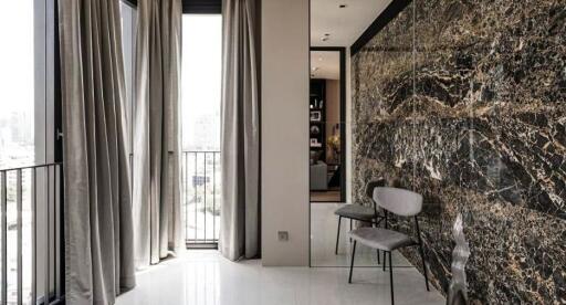 Elegant living area with floor-to-ceiling windows and marble accent wall