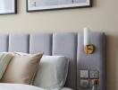 Modern bedroom with upholstered headboard and wall-mounted lamp