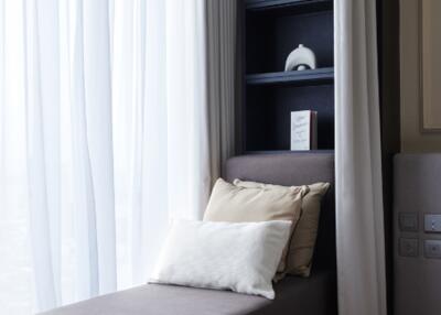 A cozy bedroom with curtains, shelves, and pillows