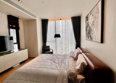 Spacious bedroom with a bed, TV, a large window with curtains, and modern furnishings