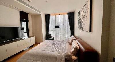 Spacious bedroom with a bed, TV, a large window with curtains, and modern furnishings