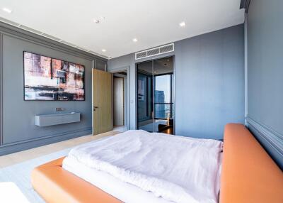 Modern bedroom with orange leather bed, large abstract painting, and city view
