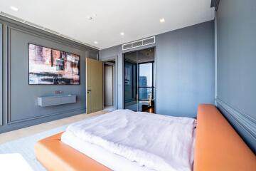 Modern bedroom with orange leather bed, large abstract painting, and city view