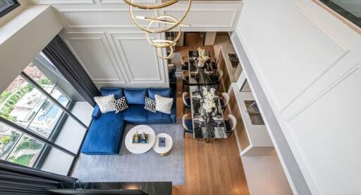 Aerial view of living and dining area with blue sofa and dining table with chairs