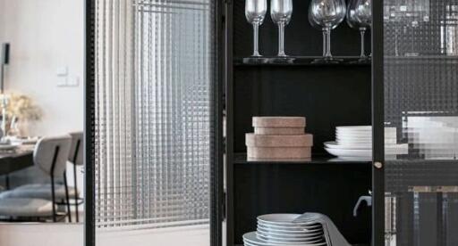 Dining area showcasing a glass cabinet with dinnerware and wine glasses