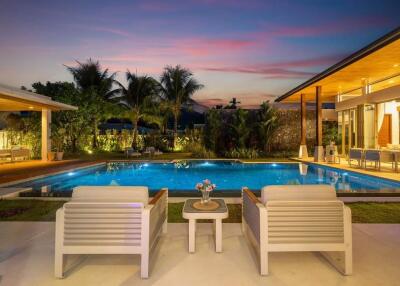 Outdoor seating area overlooking a pool at sunset