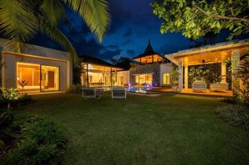 Night view of modern house with outdoor seating and well-lit garden