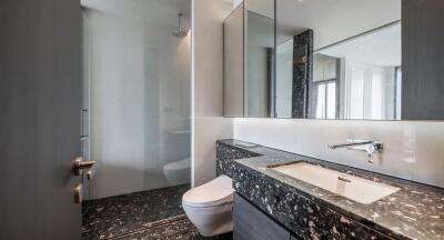 Modern bathroom with large mirror, shower, and elegant black-marble sink