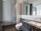 Modern bathroom with large mirror, shower, and elegant black-marble sink