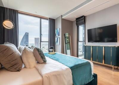 Modern bedroom with a city view, stylish decor, and a wall-mounted TV