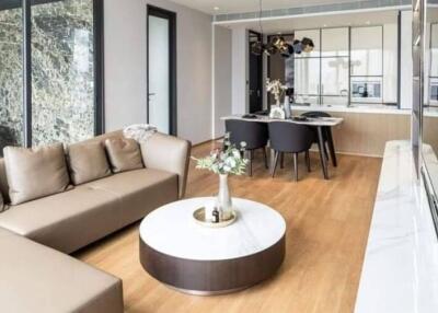 Modern living and dining area with a sectional sofa, round coffee table, dining table, and stylish lighting