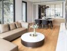 Modern living and dining area with a sectional sofa, round coffee table, dining table, and stylish lighting