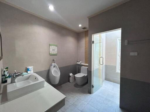 Spacious and modern bathroom with toilet, urinal, sink, and shower area