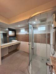 Modern bathroom with a glass shower enclosure, vanity area, and overhead lighting