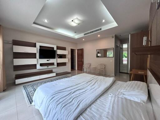 Spacious modern bedroom with built-in storage and a TV