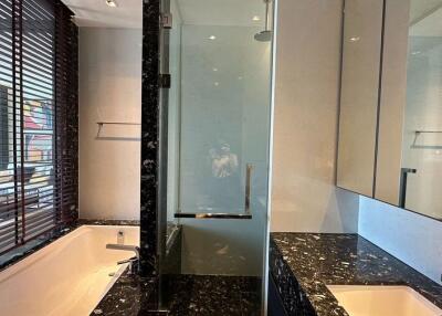 Modern bathroom with black marble countertops, bathtub, and glass shower enclosure