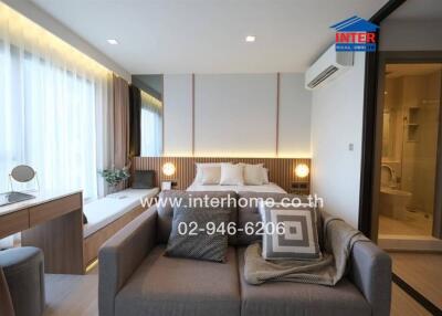 Modern bedroom with sofa, workspace, and en-suite bathroom