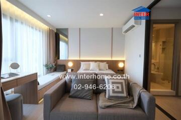 Modern bedroom with sofa, workspace, and en-suite bathroom