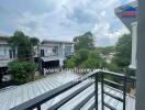 View of residential buildings from a balcony with greenery in the background