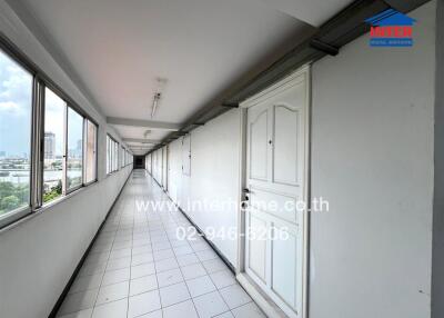Long corridor in a residential building with white doors and tiled floor