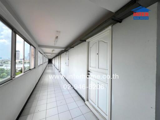 Long corridor in a residential building with white doors and tiled floor