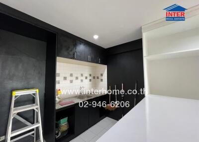 Modern kitchen with black cabinets, white countertops, and tiled backsplash.