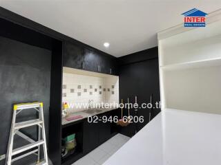 Modern kitchen with black cabinets, white countertops, and tiled backsplash.