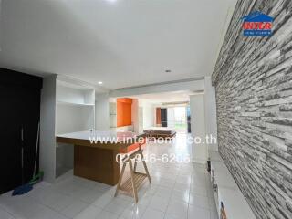 Modern open-plan living area with a breakfast bar, stone feature wall, and bright natural lighting