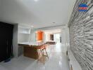 Modern open-plan living area with a breakfast bar, stone feature wall, and bright natural lighting