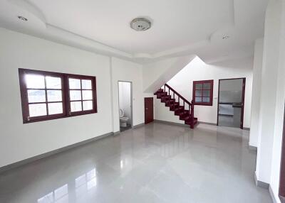 Spacious living area with ample natural light, staircase, and access to other rooms