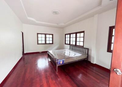 Spacious bedroom with wooden flooring and a bed
