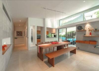 Modern dining area with wooden table and benches, large windows offering natural light