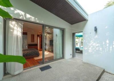 Exterior view of a modern home with a glass sliding door opening to the bedroom and patio