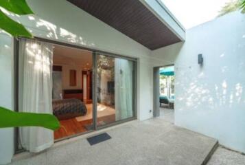 Exterior view of a modern home with a glass sliding door opening to the bedroom and patio