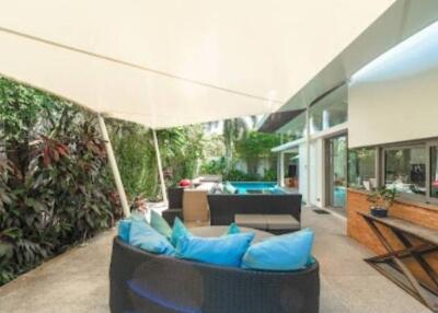 Modern outdoor seating area with blue cushions, covered patio, and greenery