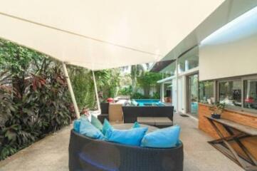 Modern outdoor seating area with blue cushions, covered patio, and greenery