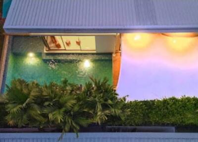 Aerial view of a modern house with a private pool and lush green landscaping