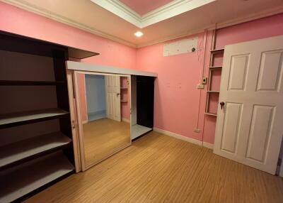 Bedroom with pink walls, wooden floor, and built-in wardrobe