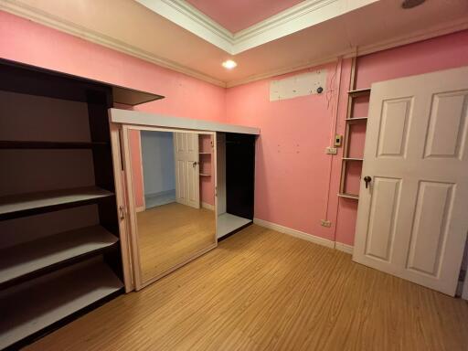 Bedroom with pink walls, wooden floor, and built-in wardrobe