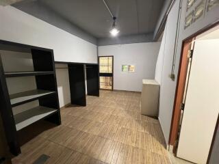 Room with wooden flooring, shelves, and a single overhead light