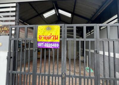 Front view of a building with a metal gate and a signboard with contact information
