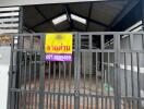 Front view of a building with a metal gate and a signboard with contact information