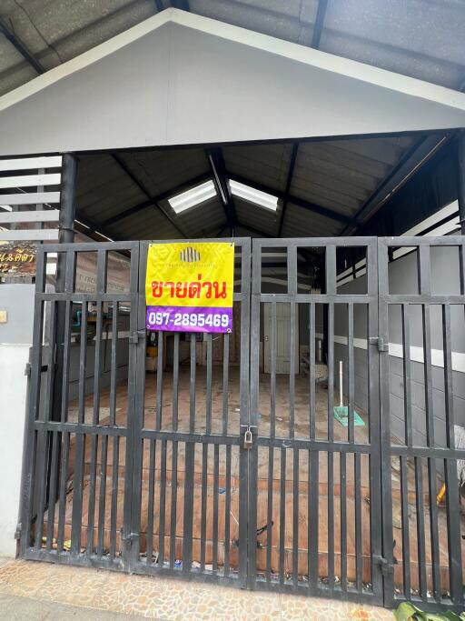 Front view of a building with a metal gate and a signboard with contact information