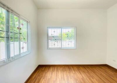Bright empty bedroom with wooden flooring and large windows