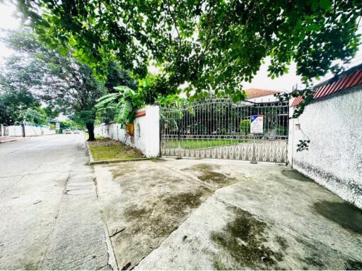 Gated property entrance with driveway and lush surroundings