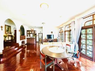 Spacious living room with dining area, wooden flooring, and large windows