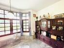 Spacious living room with large windows, wooden cabinet, and marble floor