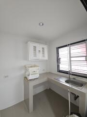 Small kitchen with white walls, single basin sink, and overhead cabinet