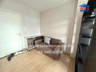 Small cozy living room with a brown sofa and a white side table.