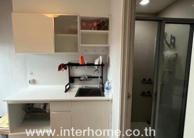 Compact kitchen area with modern cabinets and a view into the adjacent bathroom